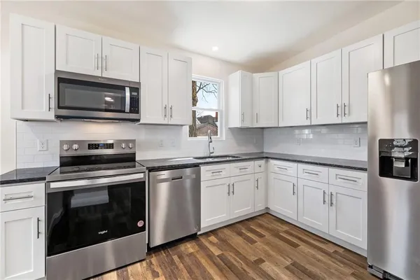a kitchen with stainless steel appliances granite countertop grey cabinets a stove a sink and a microwave