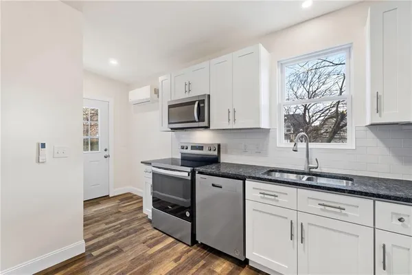 a kitchen with granite countertop a sink cabinets stainless steel appliances and a window