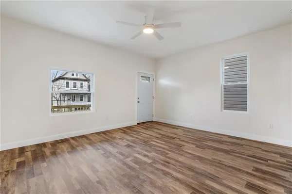 a view of an empty room with window and wooden floor