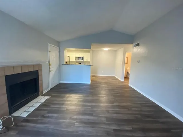 a view of empty room with wooden floor and fireplace
