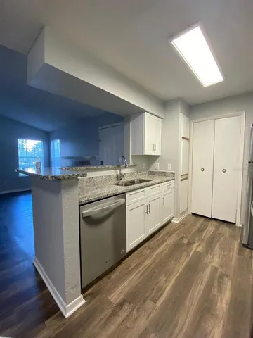 a kitchen with a white cabinets and wooden floor