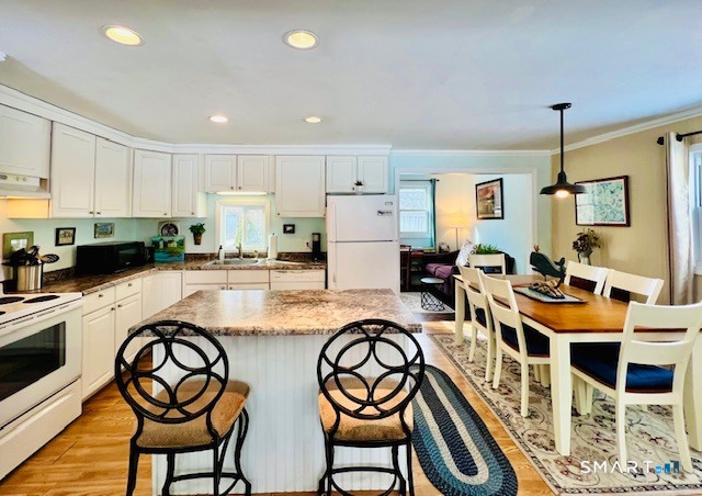 19 Old Forge Road Westbrook, CT 06498 - Photo 2 of 16 a kitchen with stainless steel appliances granite countertop a dining table chairs and white cabinets