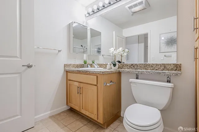 a bathroom with a granite countertop toilet sink and mirror