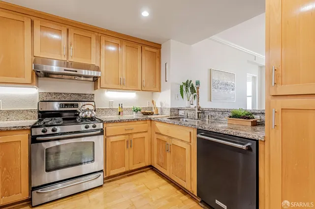 a kitchen with stainless steel appliances granite countertop a stove a sink and a refrigerator