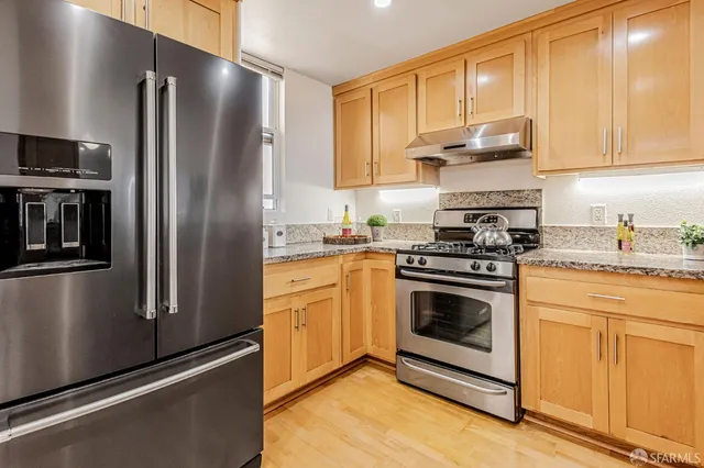 a kitchen with stainless steel appliances granite countertop a refrigerator stove and sink