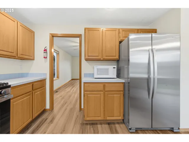 a kitchen with stainless steel appliances granite countertop a refrigerator a stove and a sink with wooden floor