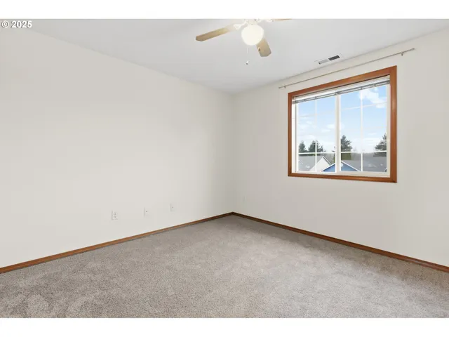 a view of an empty room and chandelier fan