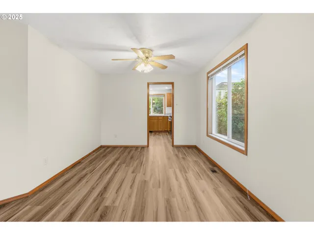 a view of an empty room with chandelier fan and wooden floor