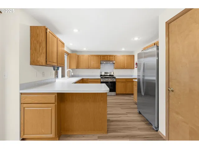 a kitchen with stainless steel appliances kitchen island granite countertop a refrigerator a stove and a sink