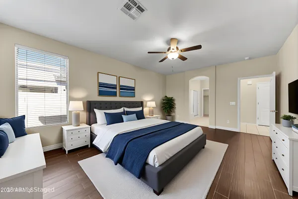 a spacious bedroom with a bed a couch and a chandelier