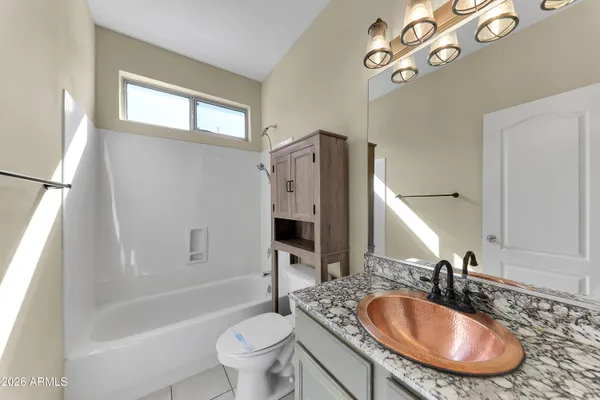 a bathroom with a granite countertop sink a toilet a mirror a bathtub and shower