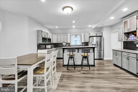 a kitchen with stainless steel appliances kitchen island granite countertop a wooden cabinets and white chairs