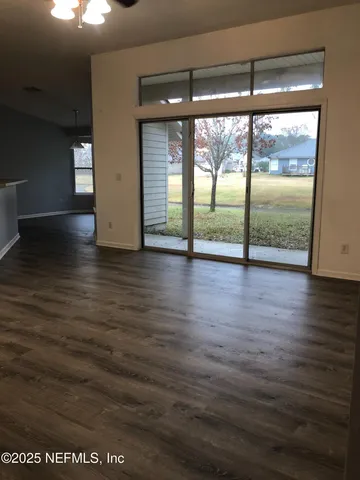 an empty room with wooden floor and windows with curtains