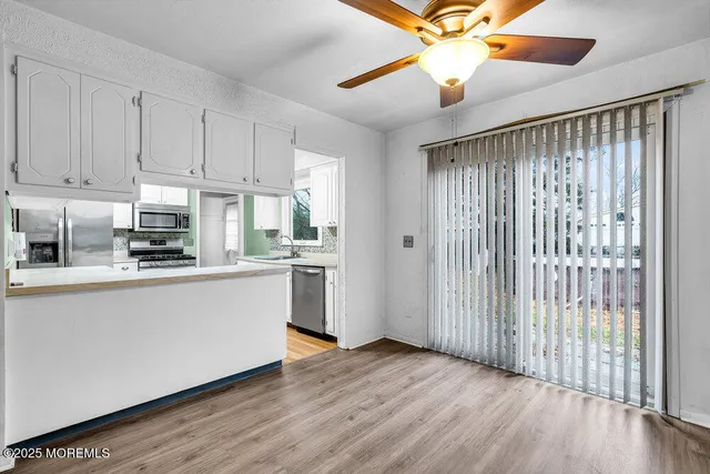 a kitchen with wooden floor a ceiling fan and windows