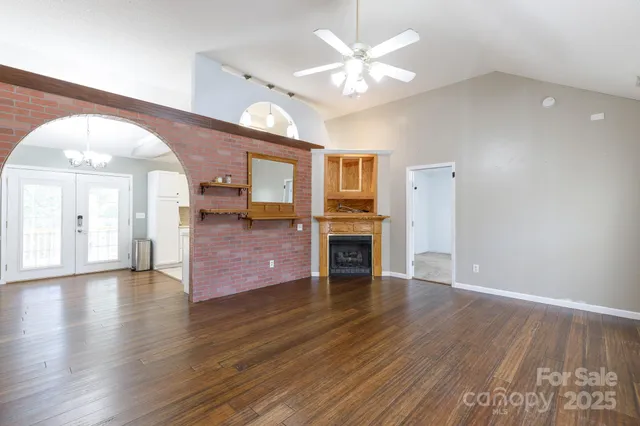 an empty room with wooden floor fireplace and windows