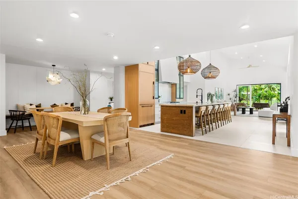 a dining hall with stainless steel appliances kitchen island granite countertop a table chairs and a view of living room
