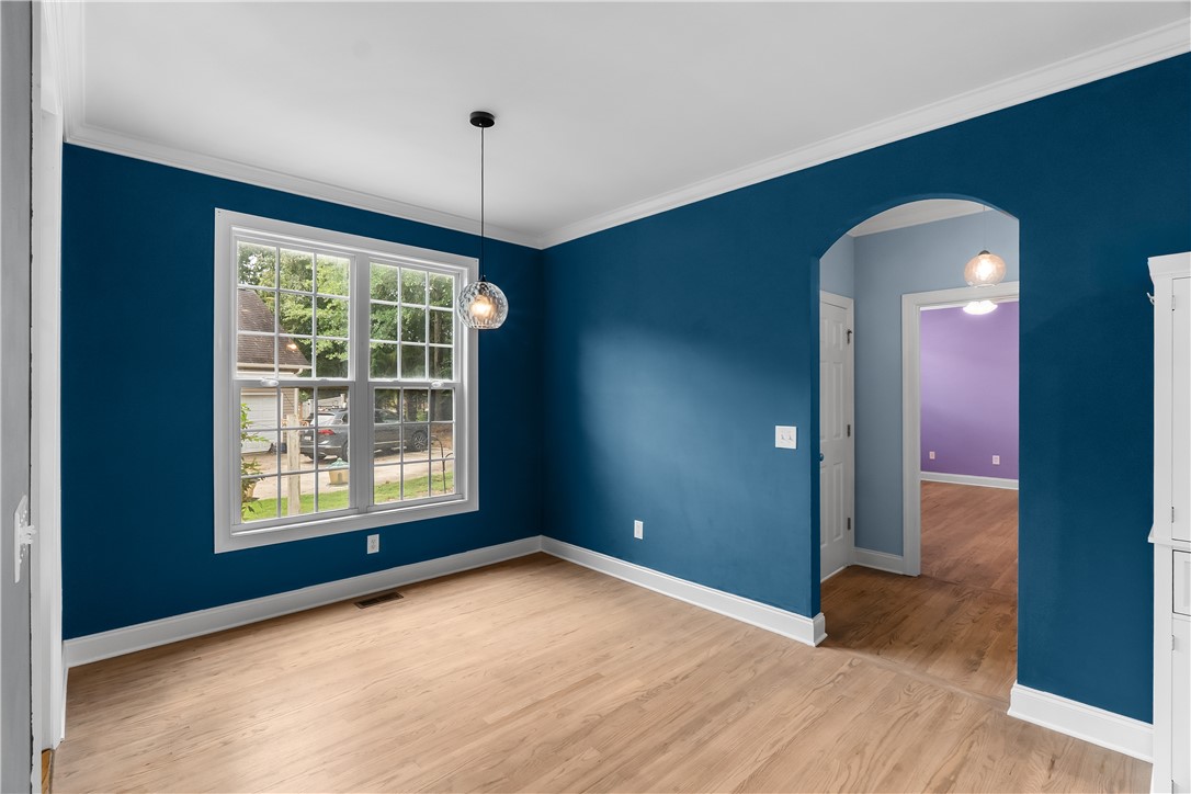 206 Village Way Pendleton, SC 29670 - Photo 9 of 46 A vibrant blue dining area features warm wood flooring and an elegant light fixture, with an arched entryway leading to an adjacent living space.