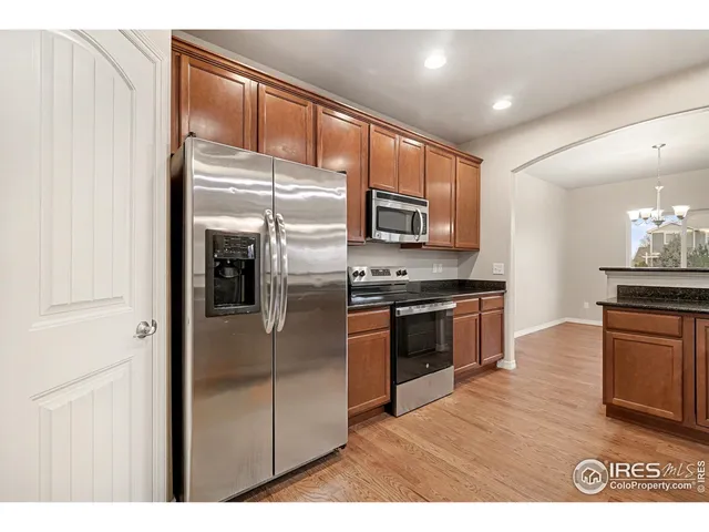 a view of a big room with wooden floor kitchen and windows