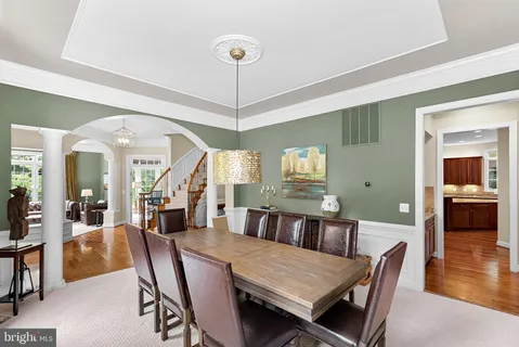 a kitchen with stainless steel appliances granite countertop a refrigerator a stove a dining table and chairs with wooden floor