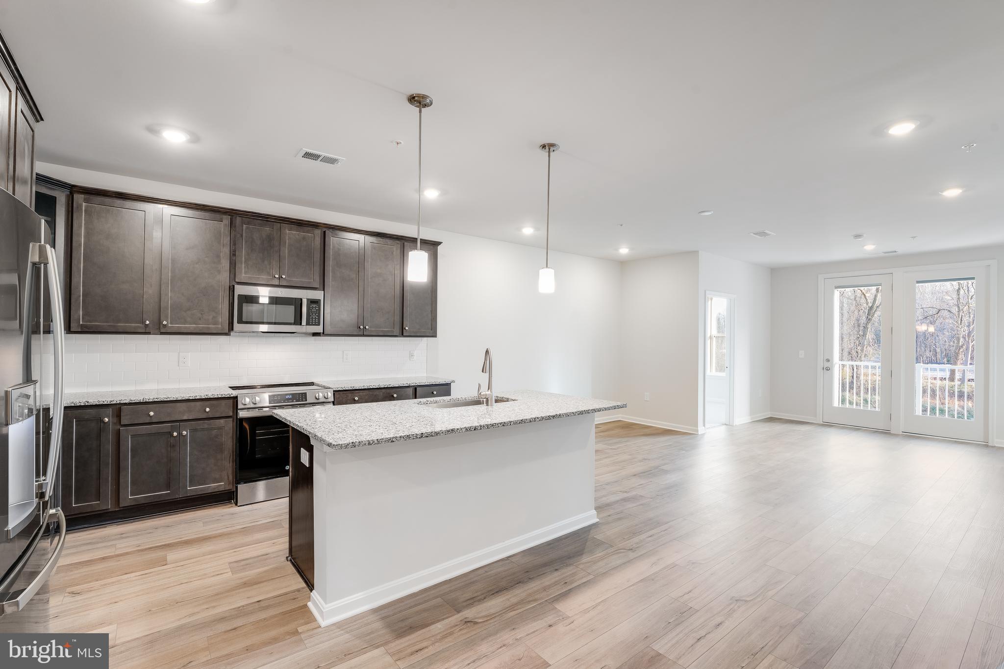 4003 Seaside Alder Road, Unit 208 ROSE Bowie, MD 20720 - Photo 2 of 18 a large kitchen with stainless steel appliances kitchen island a large counter top and a wooden floors