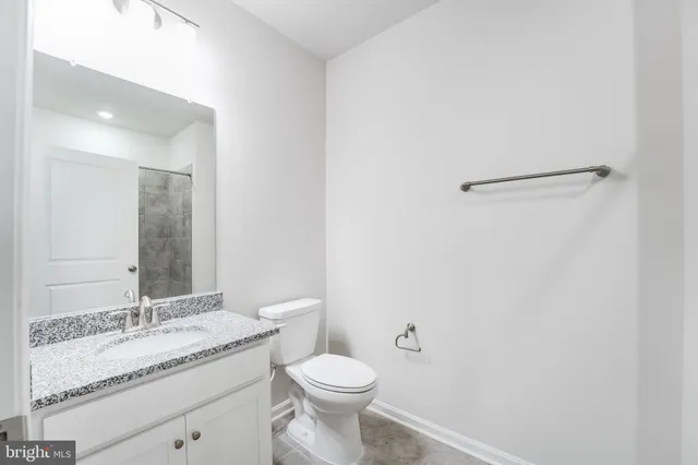 a bathroom with a granite countertop sink toilet and mirror