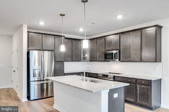 a kitchen with stainless steel appliances granite countertop a sink and a refrigerator