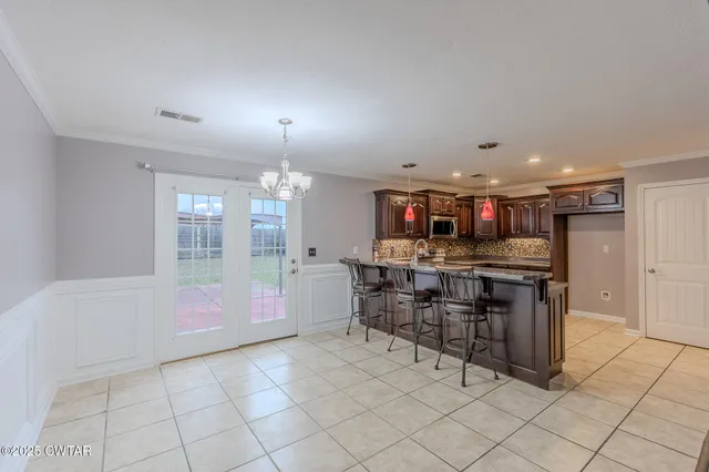 a kitchen with stainless steel appliances granite countertop a kitchen island a stove a sink a dining table and chairs