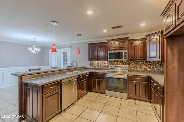 an empty room with wooden floor chandelier and windows
