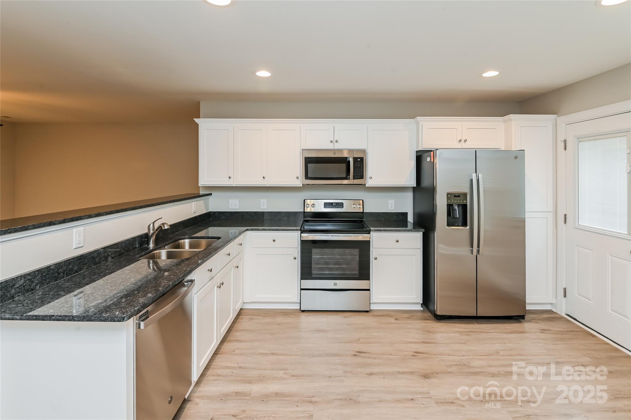 131 Powder Street Southwest Concord, NC 28025 - Photo 2 of 14 a kitchen with stainless steel appliances granite countertop a stove a refrigerator and a microwave