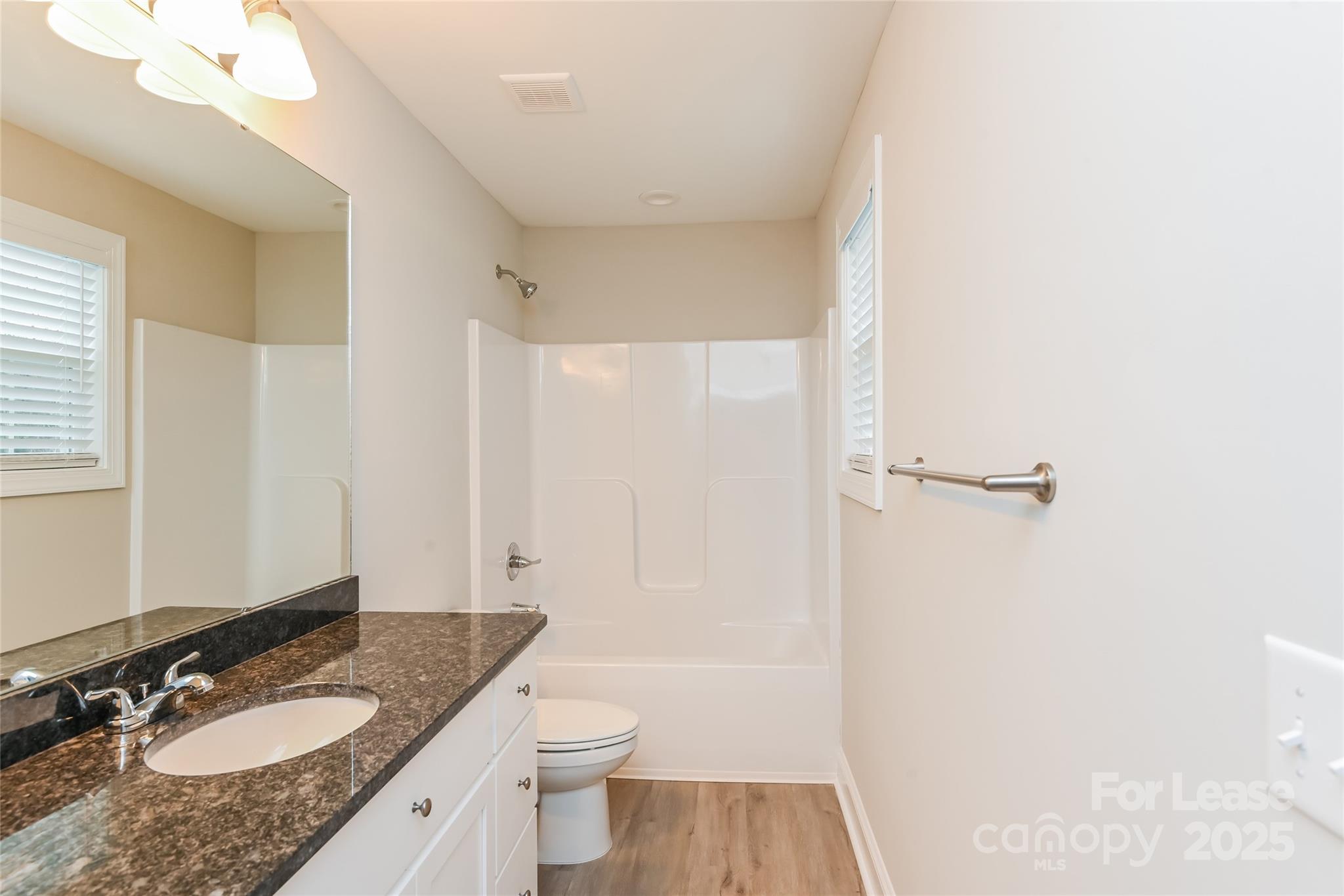131 Powder Street Southwest Concord, NC 28025 - Photo 9 of 14 a bathroom with a granite countertop sink toilet a mirror and shower
