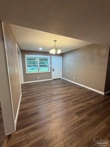 an empty room with wooden floor and chandelier