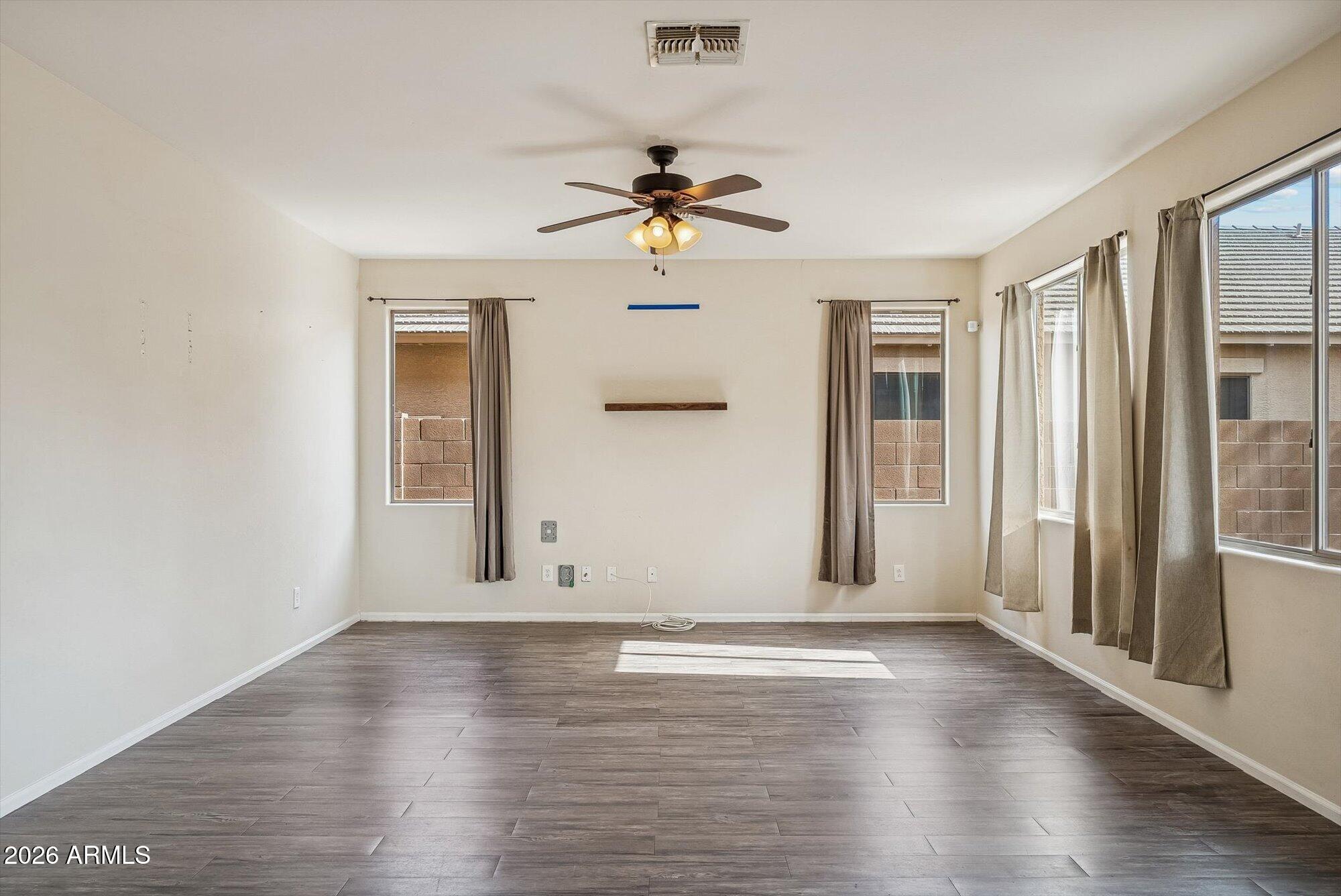 3903 East Citrine Road San Tan Valley, AZ 85143 - Photo 9 of 34 an empty room with wooden floor ceiling fan and windows