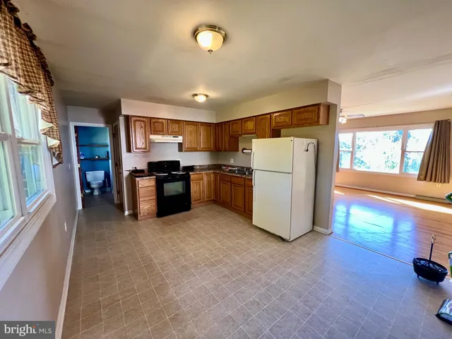 a kitchen with granite countertop a refrigerator stove top oven and cabinets