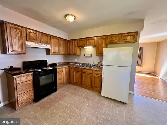 a view of kitchen with refrigerator cabinets and furniture