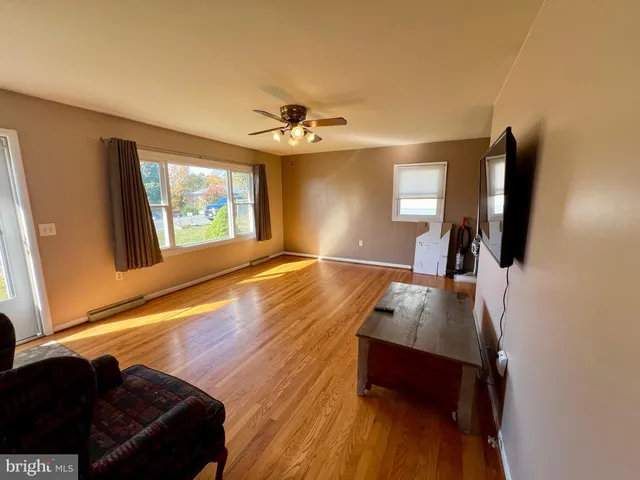 a living room with hardwood floor furniture and a large window