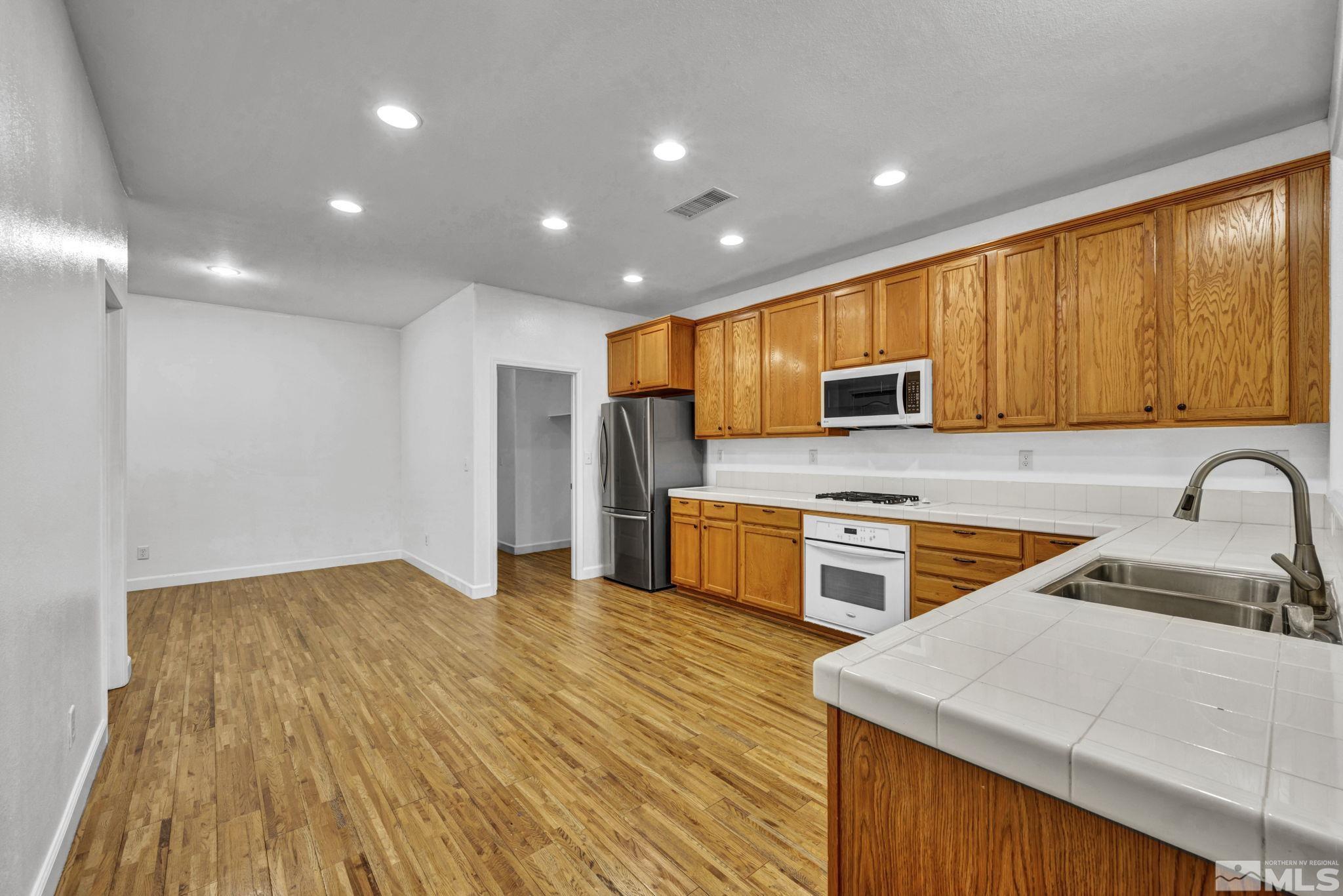 11275 Torino Way Reno, NV 89521 - Photo 13 of 37 a kitchen with stainless steel appliances granite countertop wooden cabinets a stove top oven a sink and dishwasher with wooden floor
