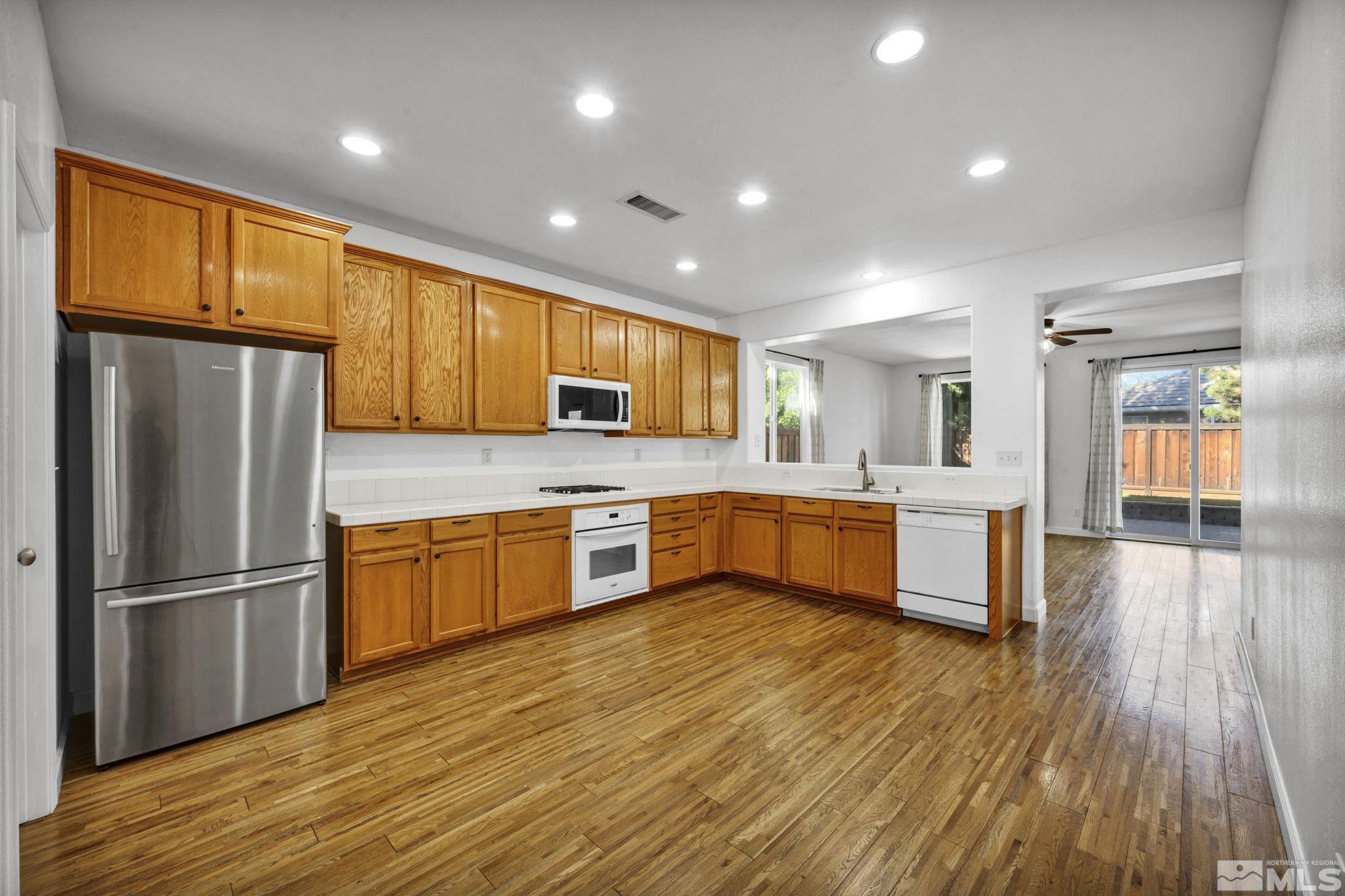 11275 Torino Way Reno, NV 89521 - Photo 14 of 37 a large kitchen with stainless steel appliances wooden floors and wooden cabinets