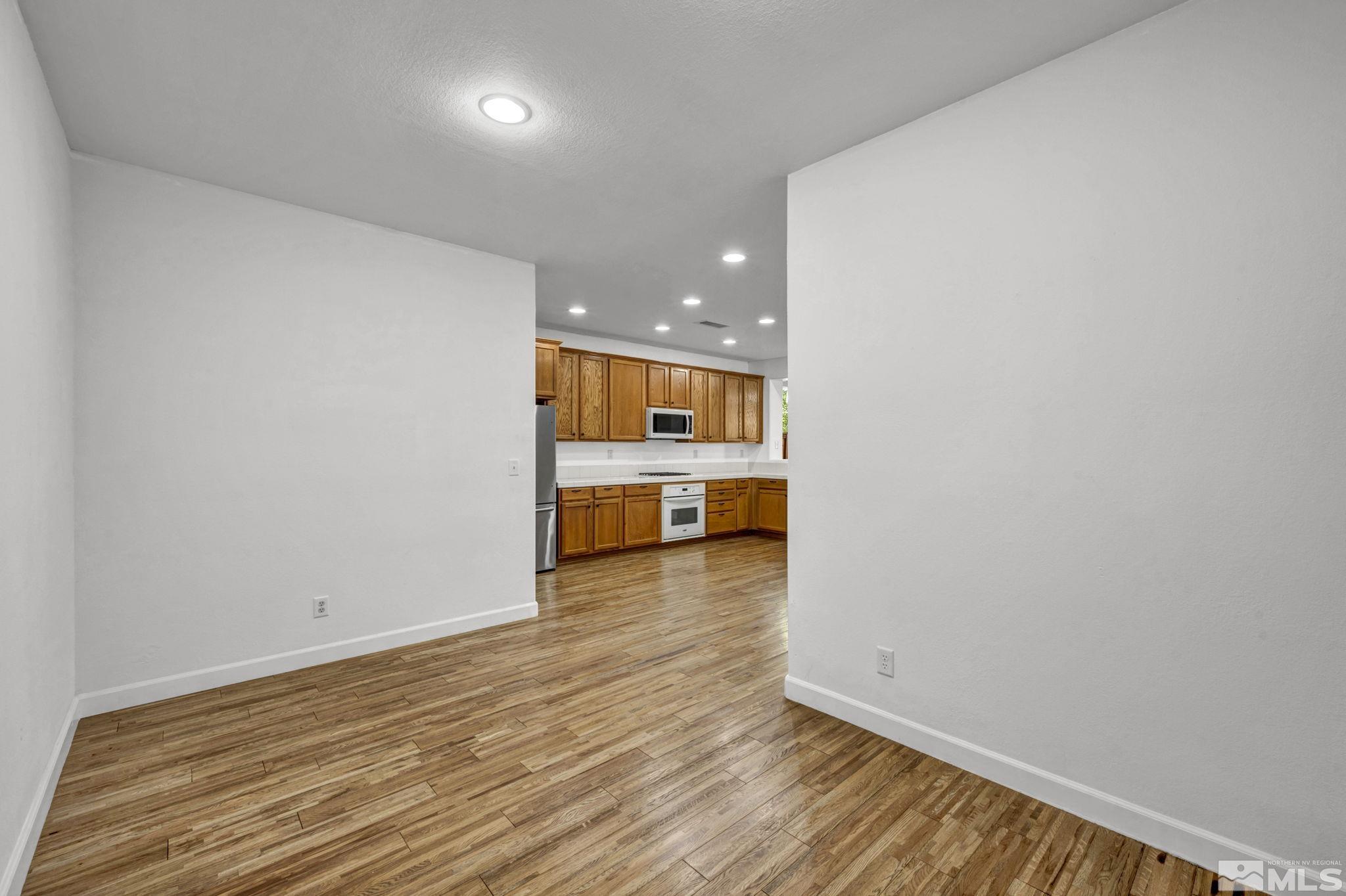 11275 Torino Way Reno, NV 89521 - Photo 16 of 37 a view of an empty room with wooden floor and a kitchen