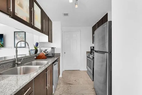 a kitchen with stainless steel appliances granite countertop a sink and a refrigerator