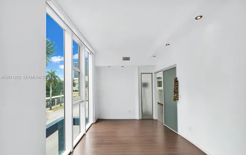 a view of a hallway with wooden floor and a bathroom
