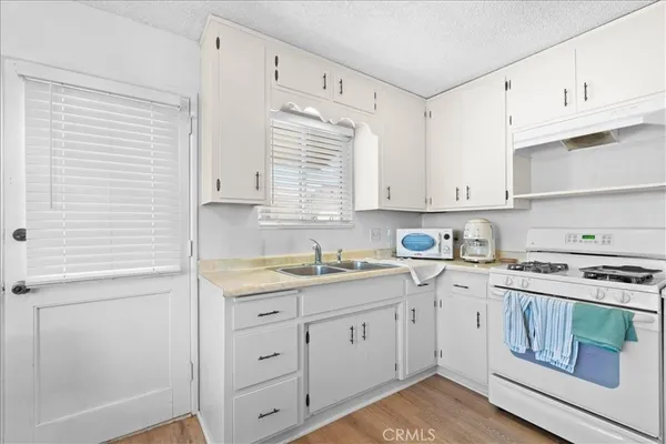 a kitchen with stainless steel appliances a refrigerator a stove a sink and white cabinets