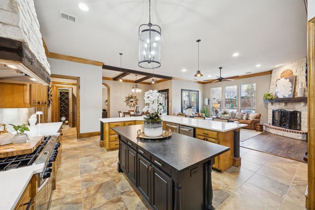 4290 Castle Bank Lane Frisco, TX 75033 - Photo 9 of 40 a kitchen with granite countertop a stove a sink a refrigerator and a dining table with wooden floor