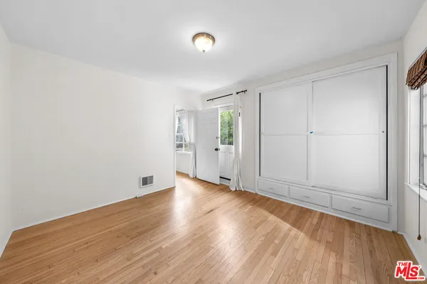 a view of an empty room with wooden floor and a window