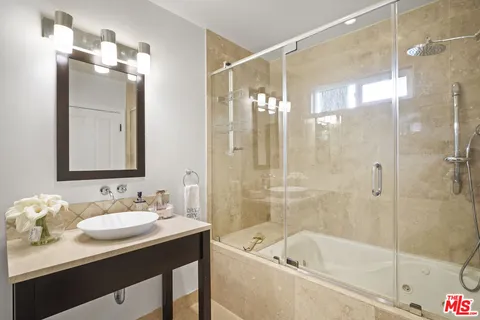 a bathroom with a bath tub sink mirror and shower
