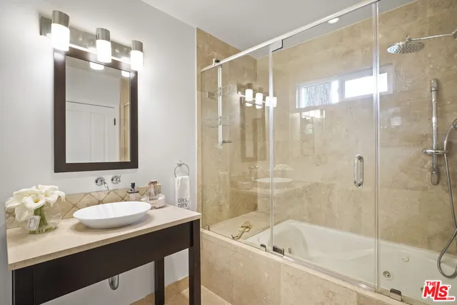 a bathroom with a bath tub sink mirror and shower