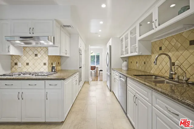 a large kitchen with kitchen island granite countertop a sink and cabinets