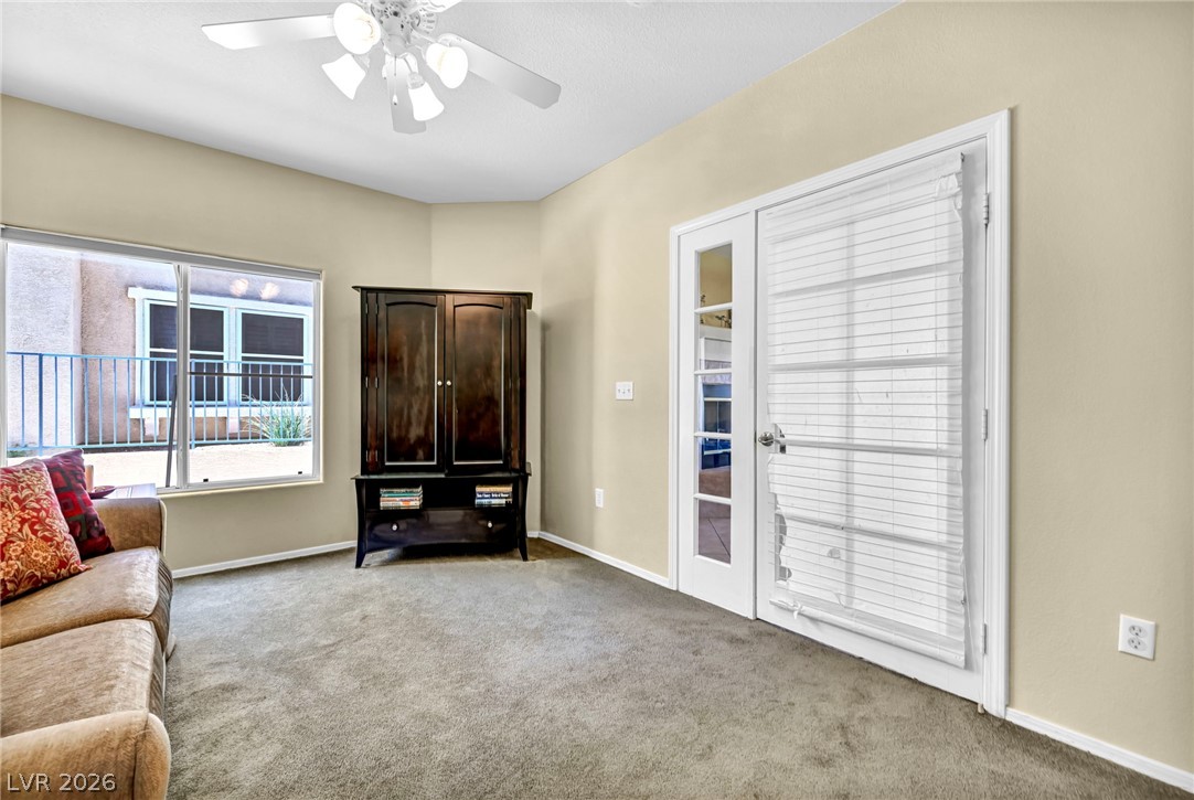 10730 Amber Ridge Drive, Unit 101 Las Vegas, NV 89144 - Photo 7 of 32 A versatile living area features carpeted floors and a glass paneled door leading to an adjacent room.