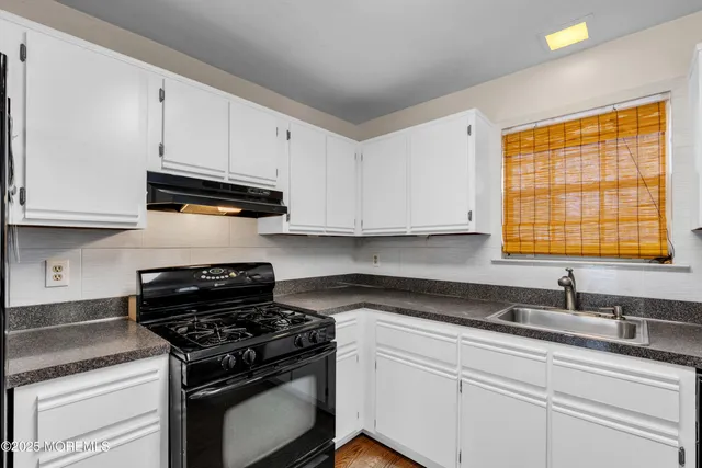a kitchen with granite countertop white cabinets and appliances