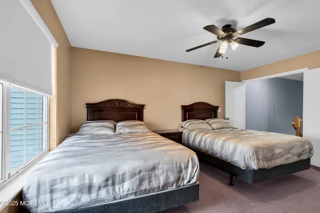 a bedroom with two beds and ceiling fan