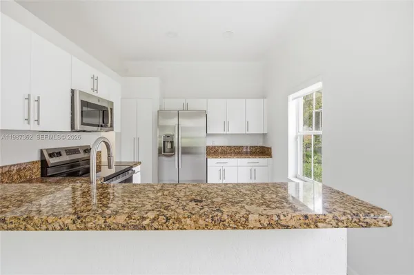 a kitchen with granite countertop a sink stove and microwave